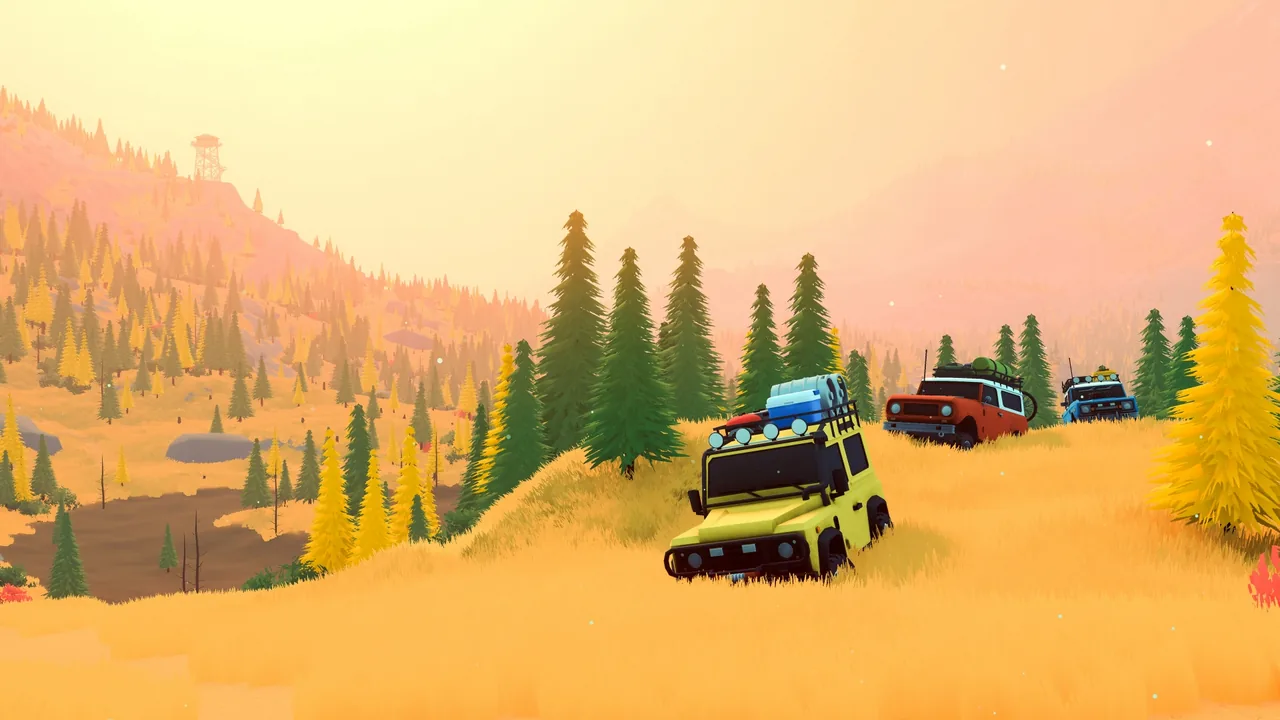 A yellow boxy off-roader with a roof basket drives through tall golden grass on a hillside, followed by a red and a blue off-roader, with a fire lookout tower on the ridge.